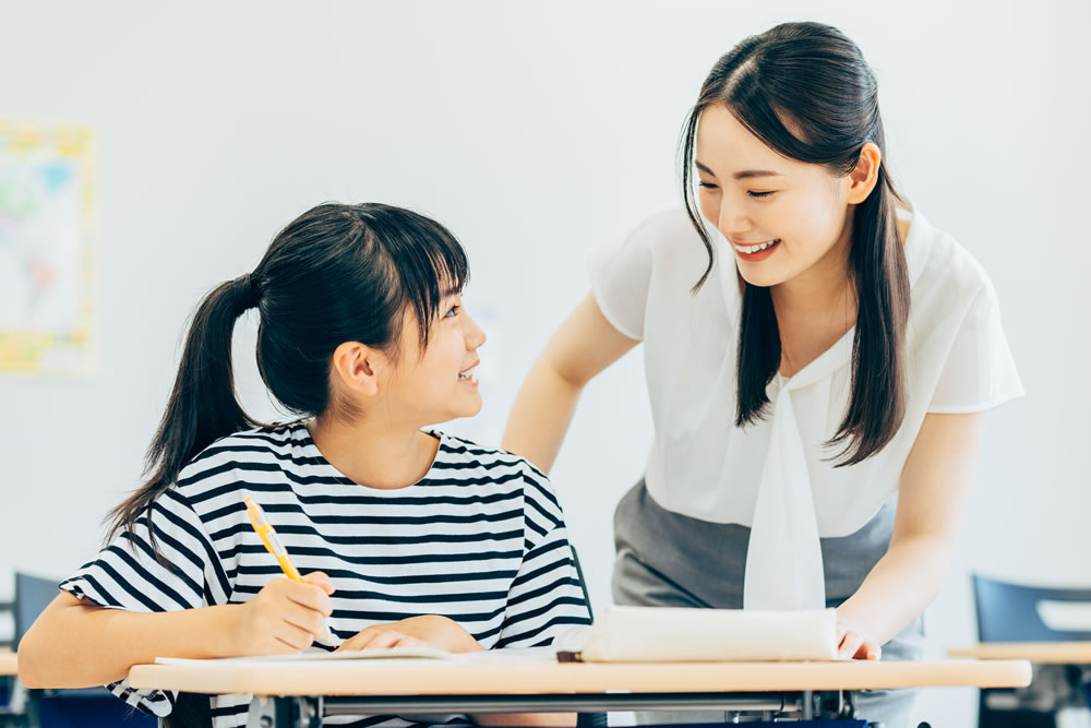 個別指導の塾で先生と仲良く話す生徒